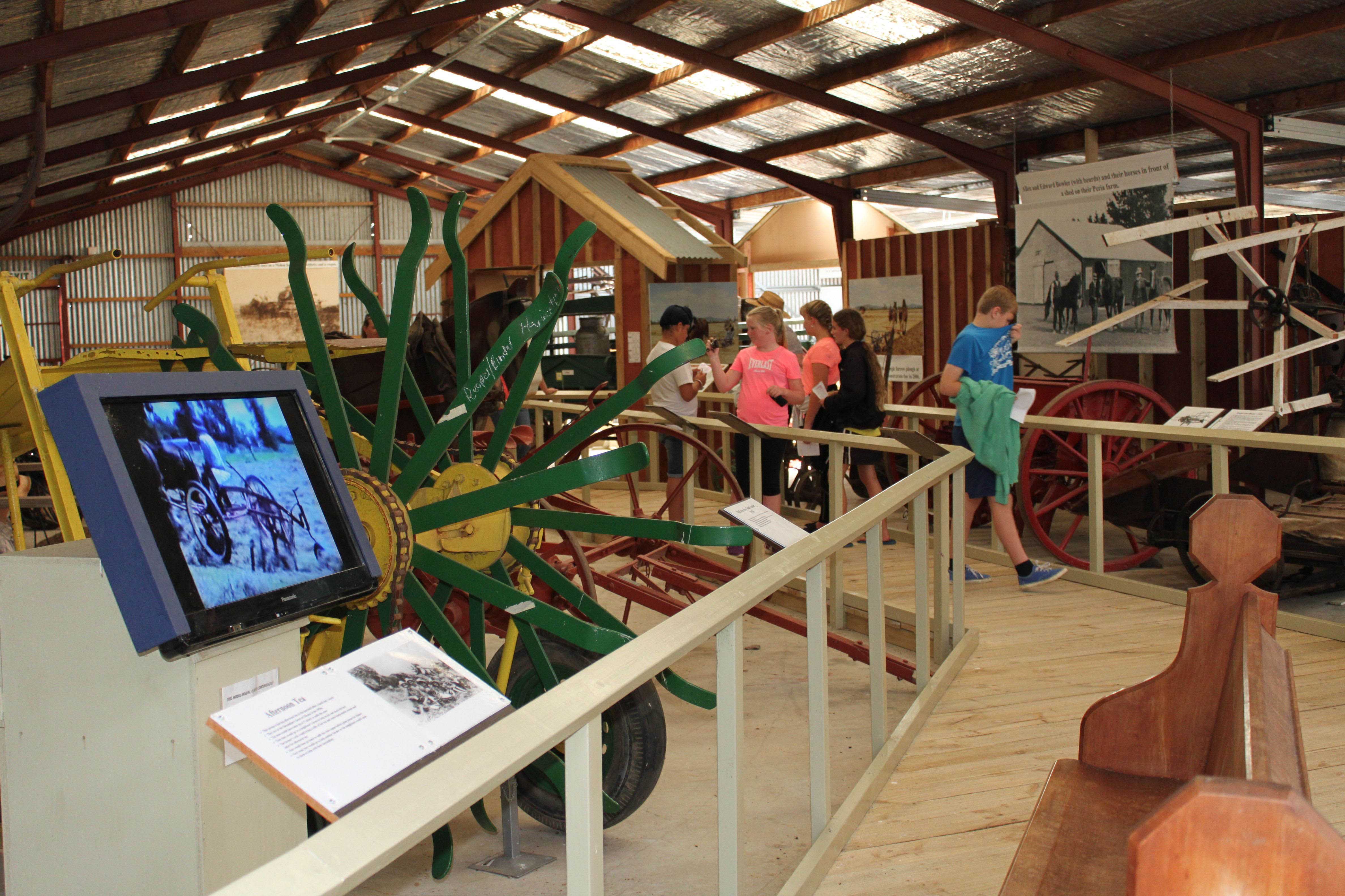 Group of visitors to the Museum viewing articles inside a large barn