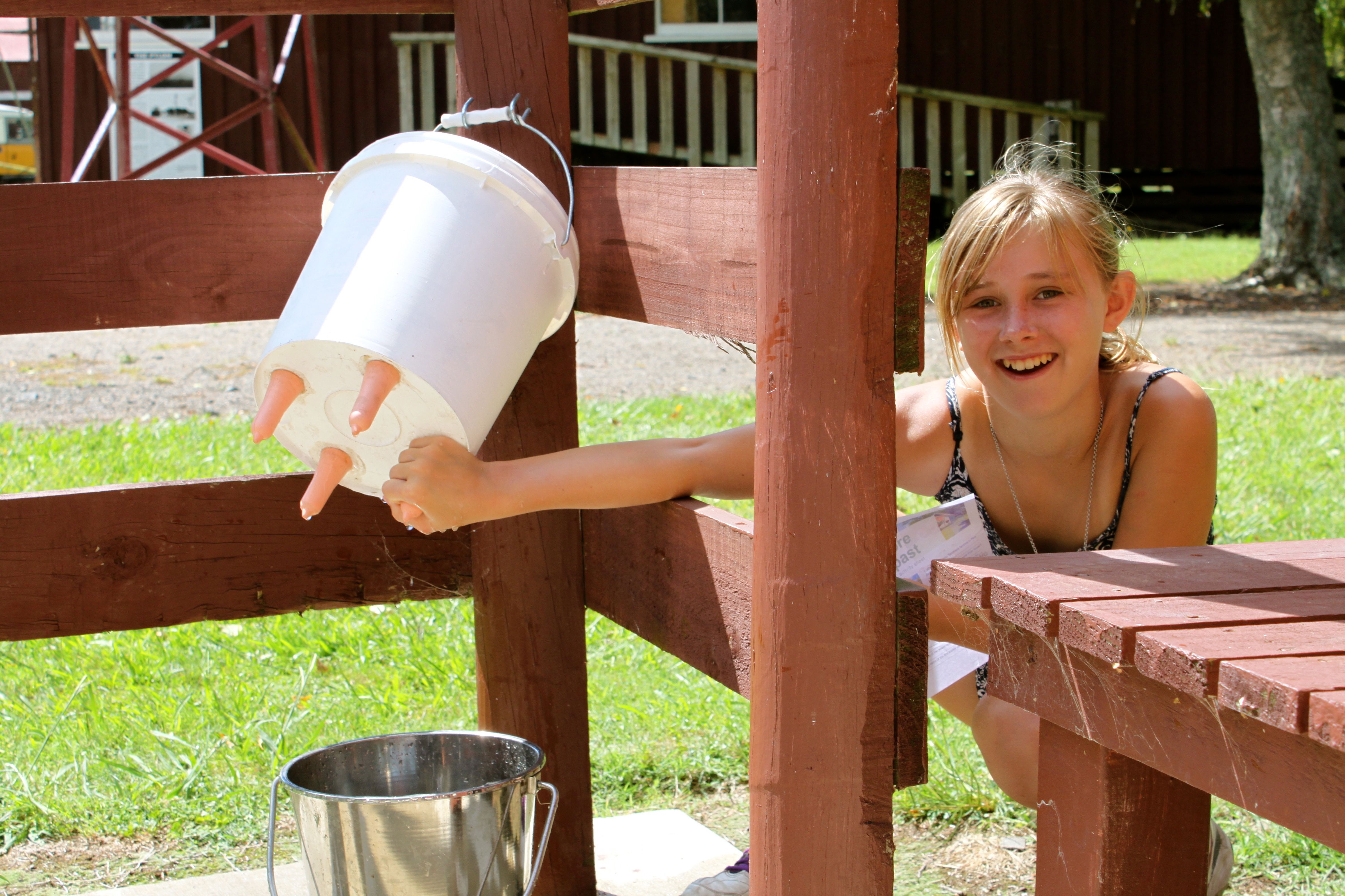 Girl holding end of a feeding bucket for animals