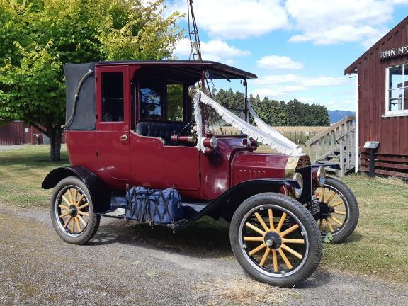 A vintage car decked out with wedding ribbons 